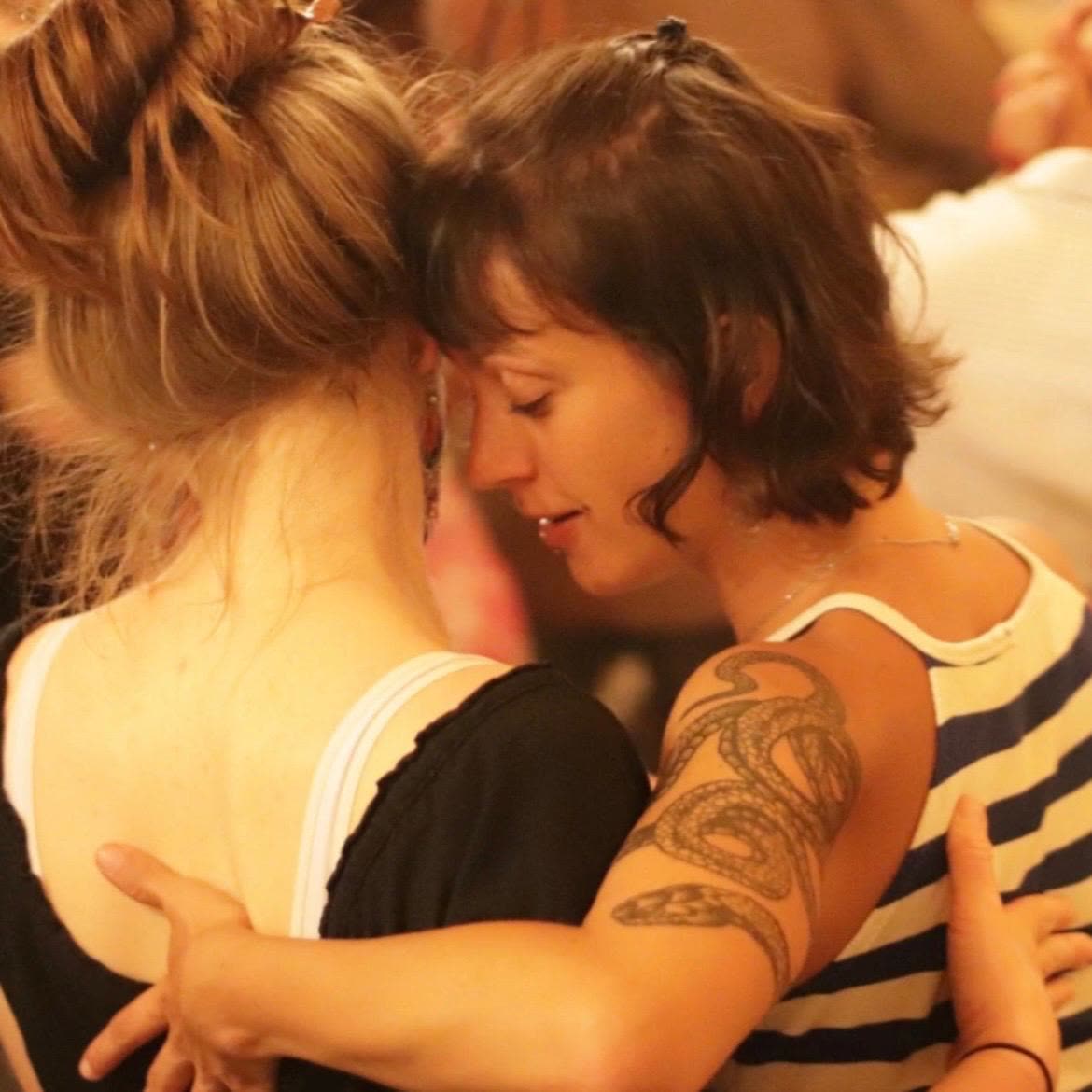 Two dancers resting forehead to forehead in the embrace